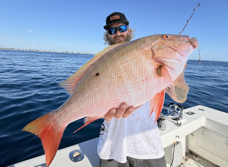 Captain Adam Hastings holding a mutton snapper aboard Strike Mission