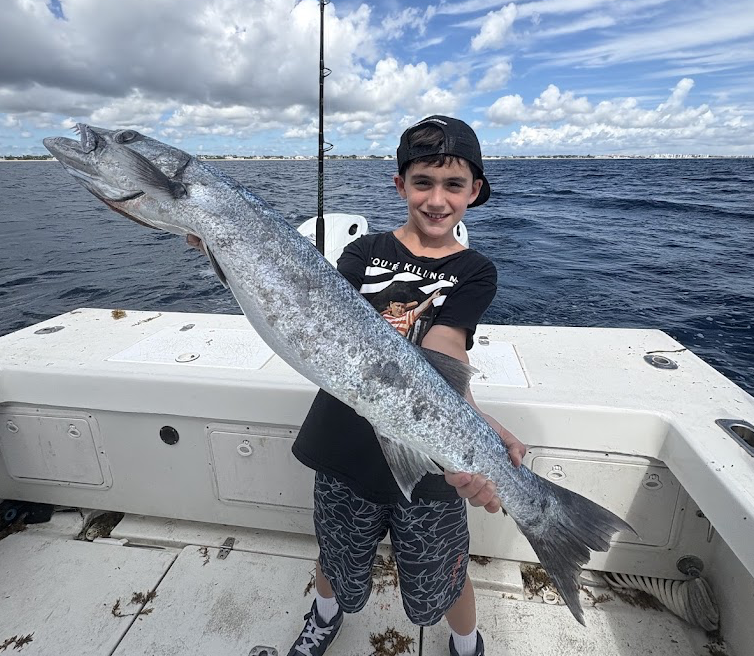 Young angler with a large barracuda aboard Strike Mission